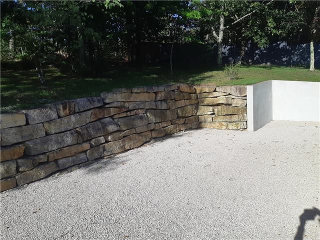 Muret en pierre et allée claire dans un jardin