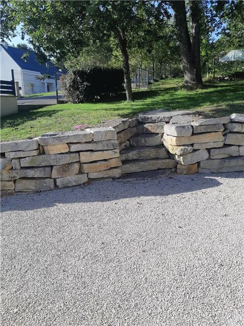 Muret en pierre naturelle bordant une allée gravillonnée