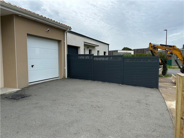 Clôture grise avec portail devant un garage