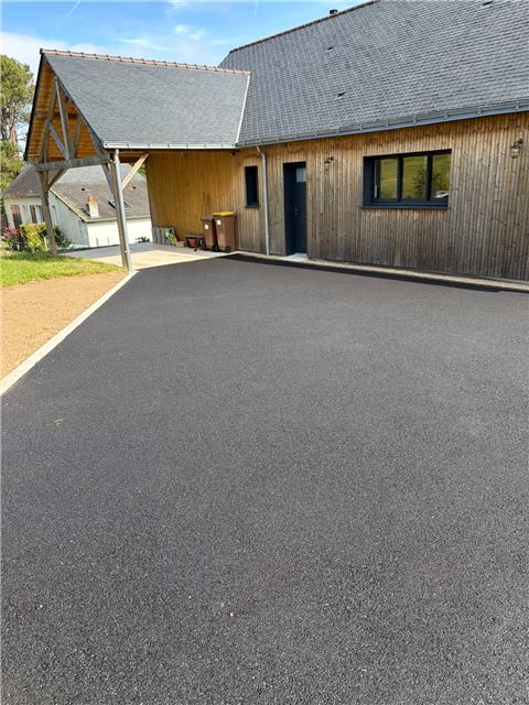 Cour en enrobé devant une maison et un garage